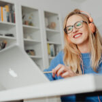 Woman running online class on laptop wearing headphones